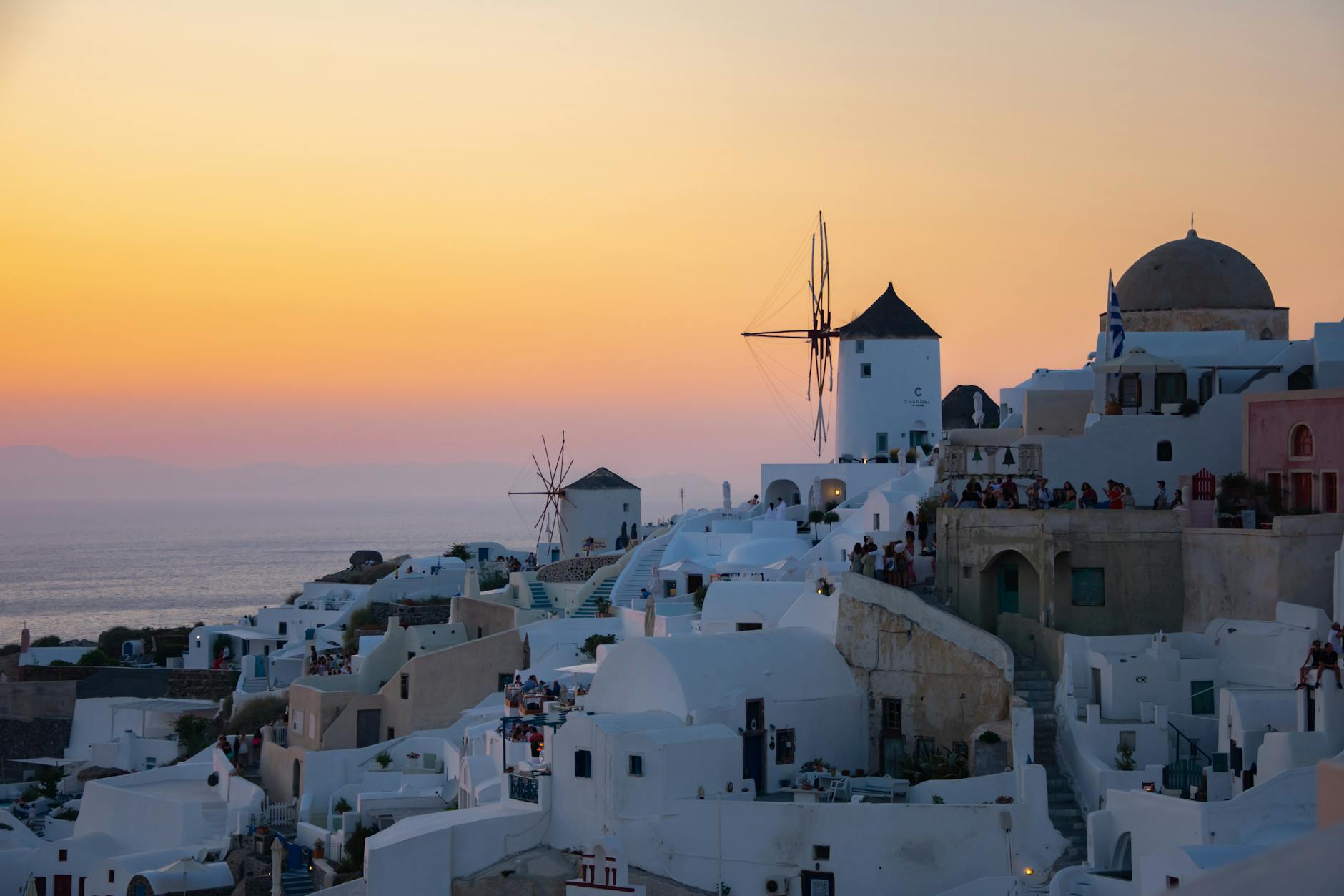 Experience the stunning sunset in Santorini, Greece, showcasing iconic white architecture and windmills.
