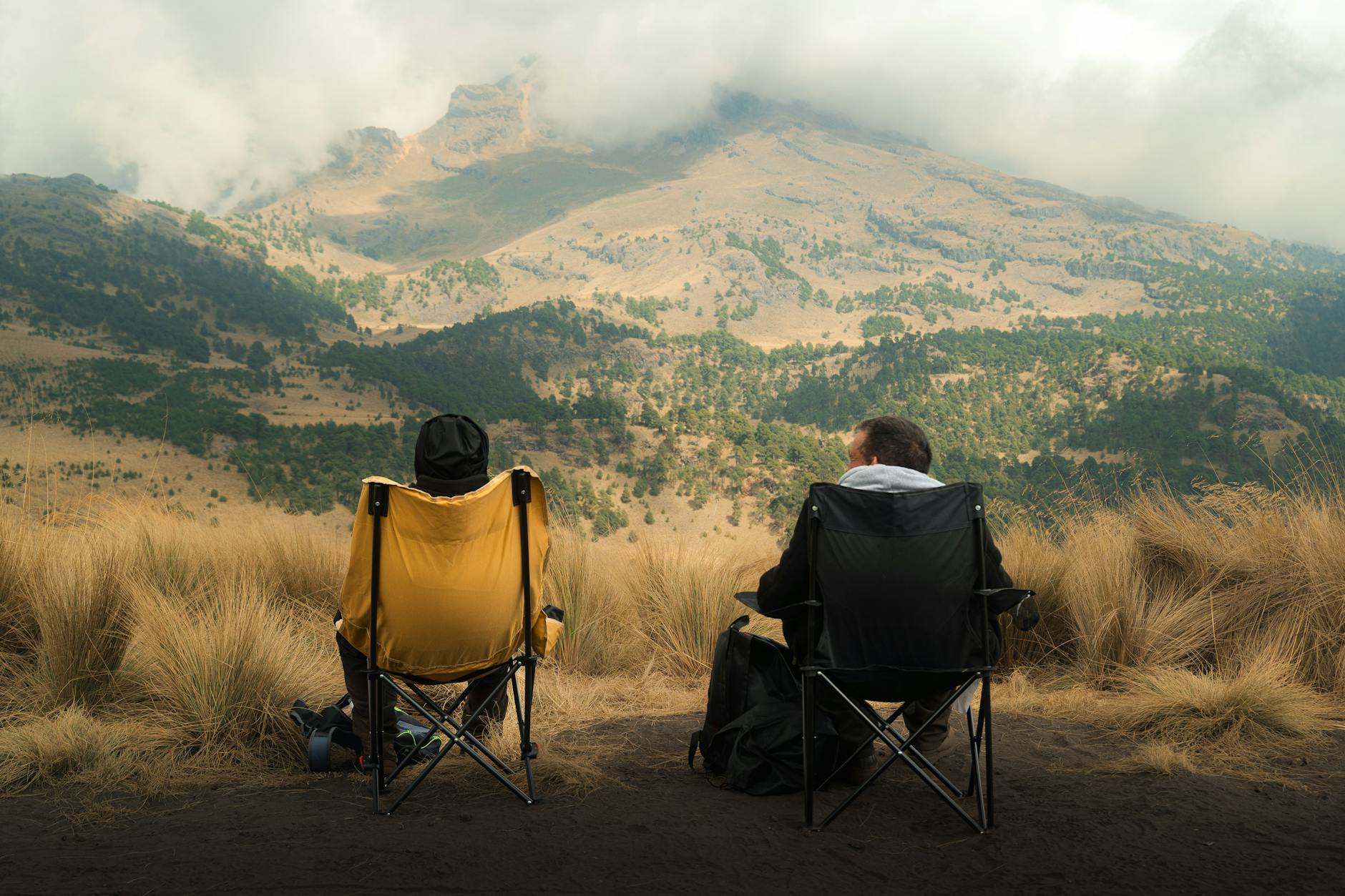 Two people enjoying scenic mountain views from camping chairs in Pue., Mexico.