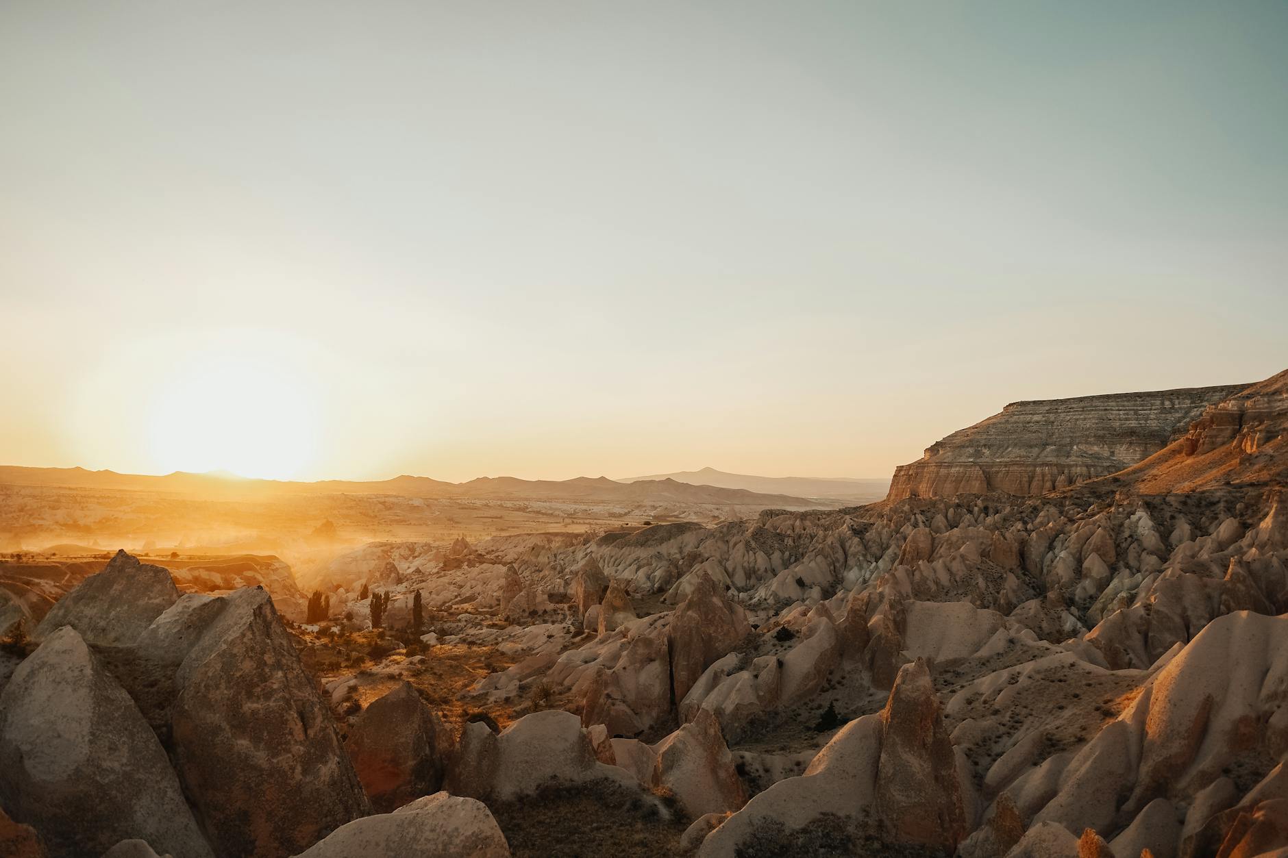 Beautiful sunrise over a rocky desert landscape with sun peeking above the horizon.