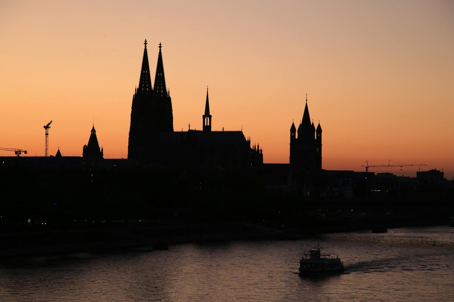 Dramatic silhouette of Cologne Cathedral and Rhine River at sunset.