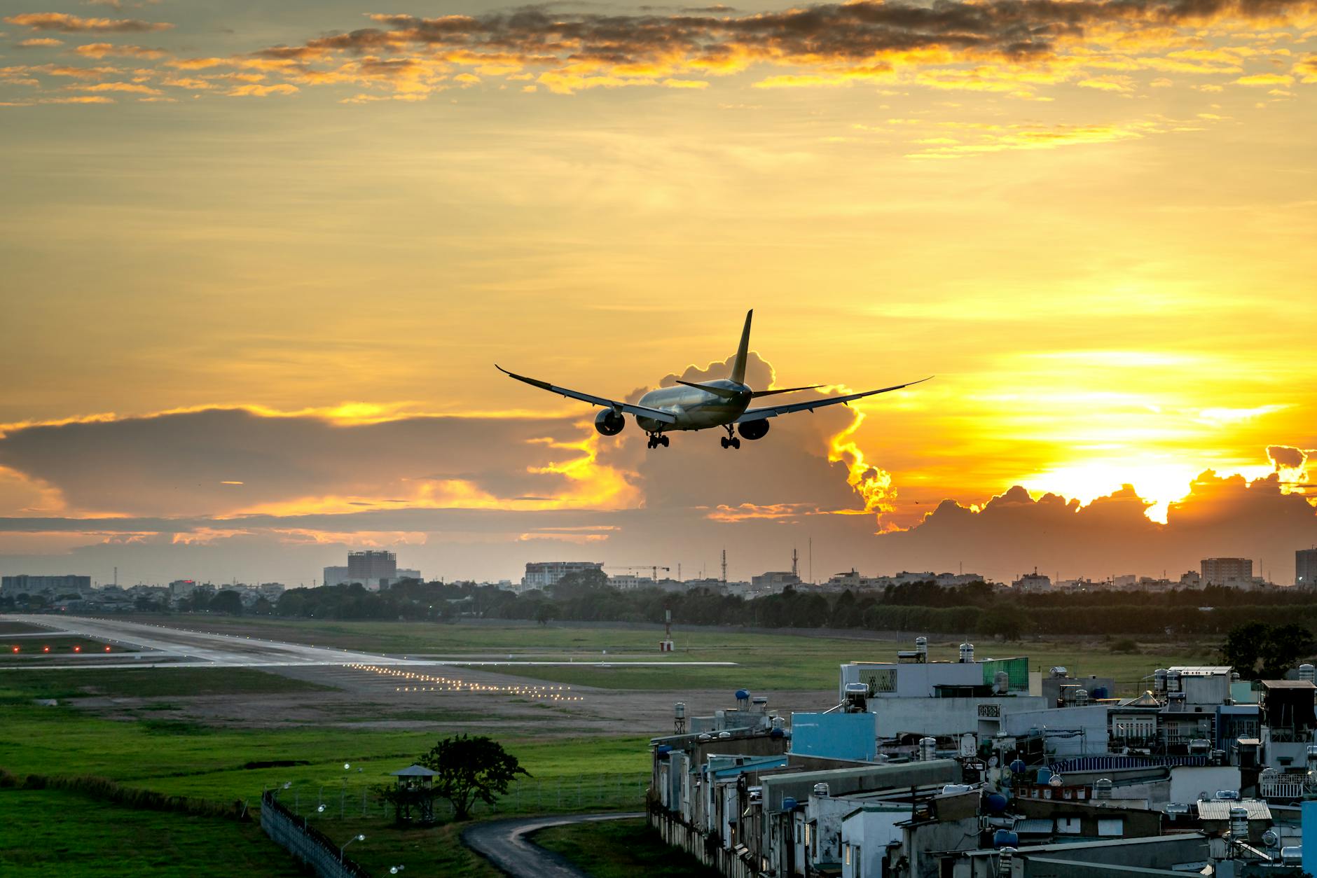 Airplane approaching runway during a vibrant sunset, perfect for travel and aviation themes.