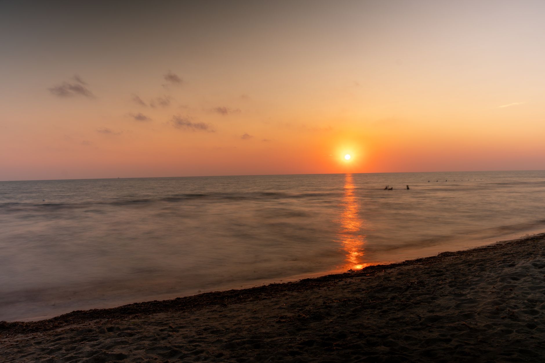 Peaceful sunset over an Italian beach with golden hues reflecting on the calm sea.