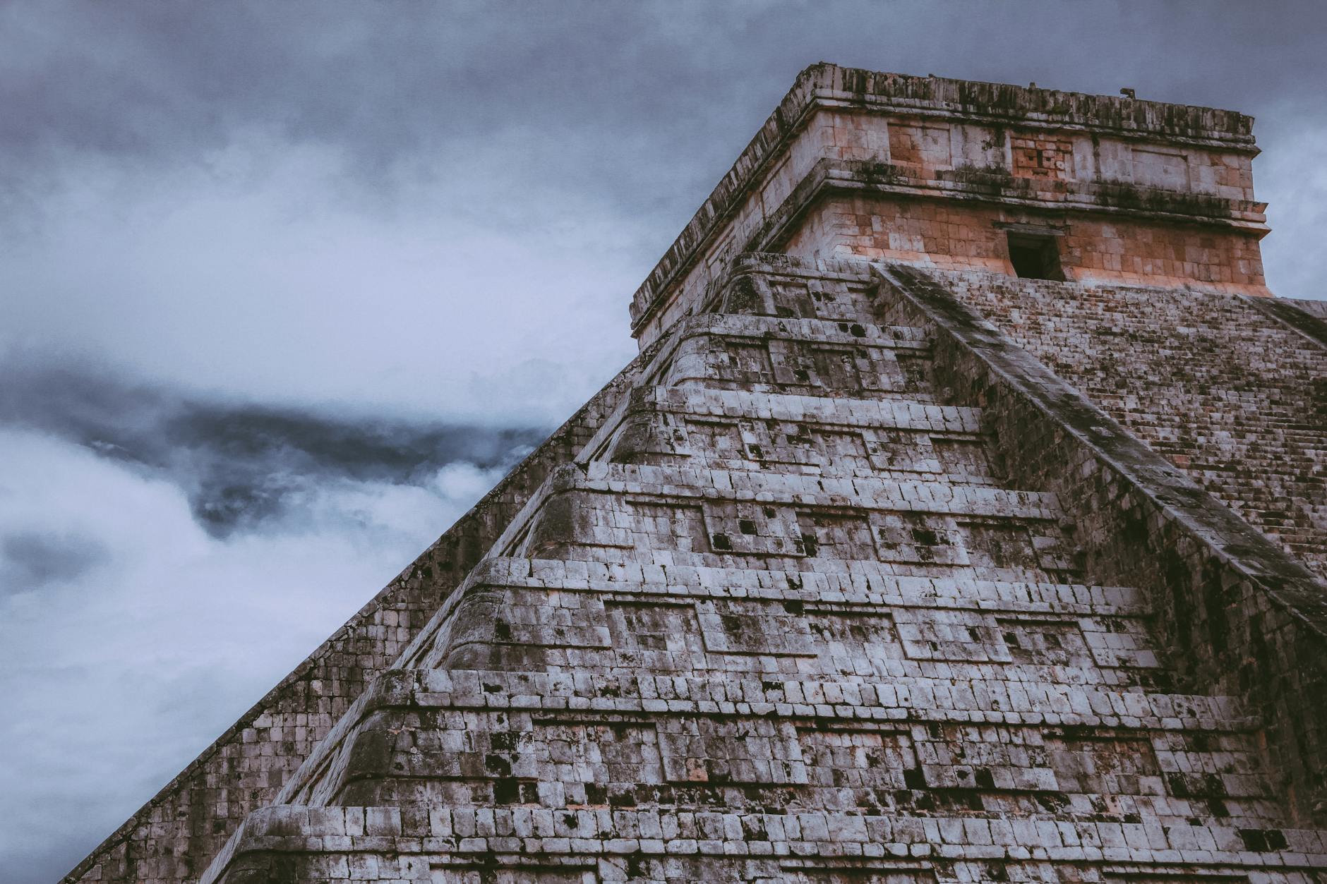 A stunning view of the ancient pyramid at Chichen Itza, Mexico under a moody sky.