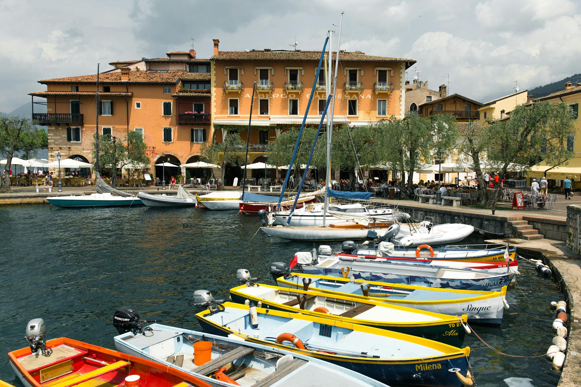 Explore a picturesque lakeside village in Italy with colorful boats docked at the serene harbor.
