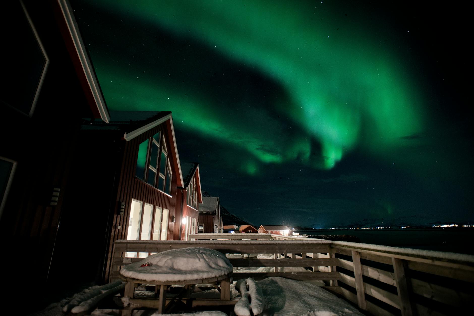 Beautiful view of the Northern Lights dancing over snowy village homes under a starry night.