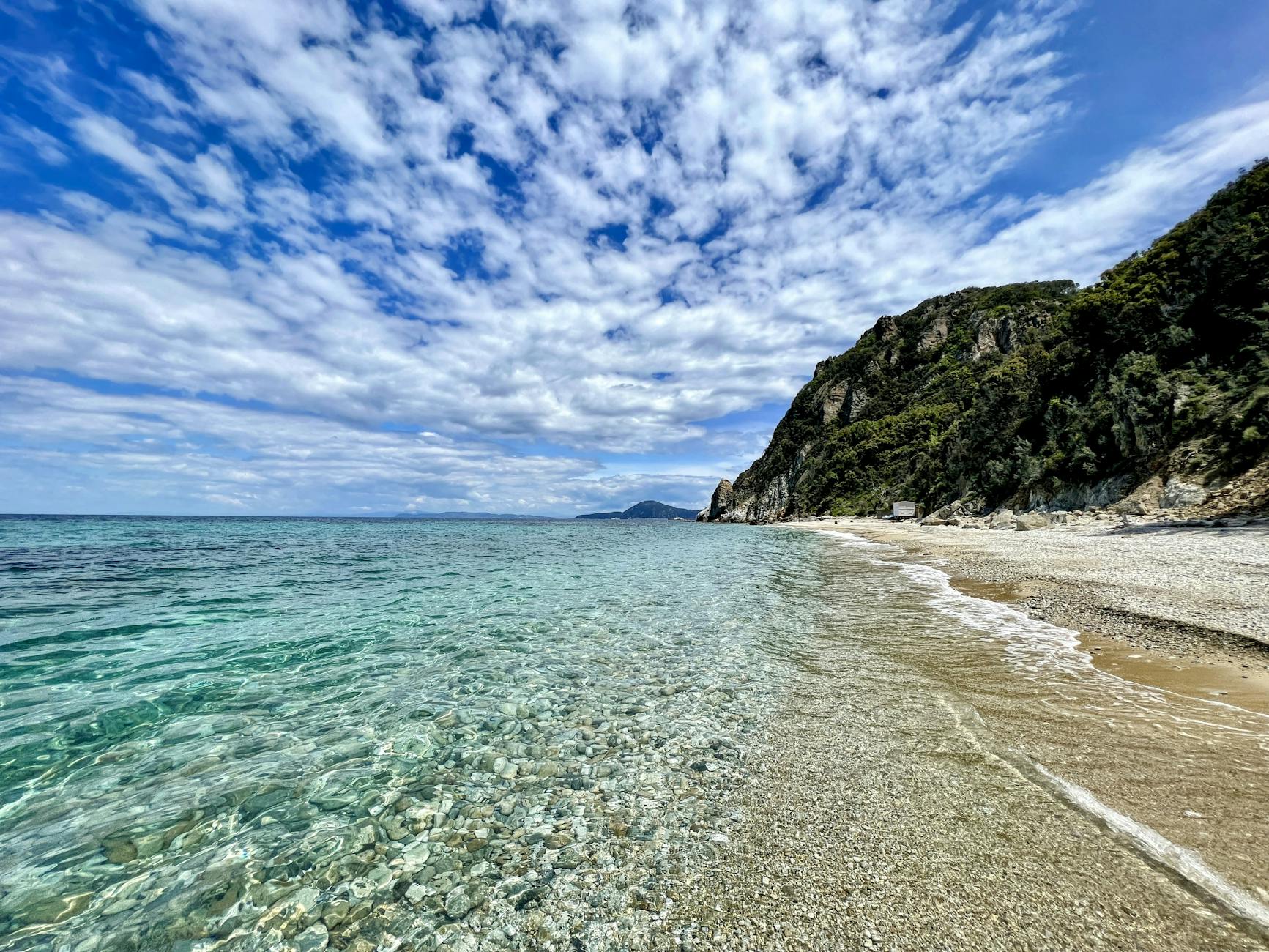 Stunning beach scene on Elba Island featuring clear blue waters and rocky cliffs under a vibrant sky.